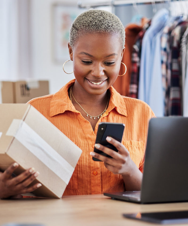 Small business clothing store owner looking at her phone smiling