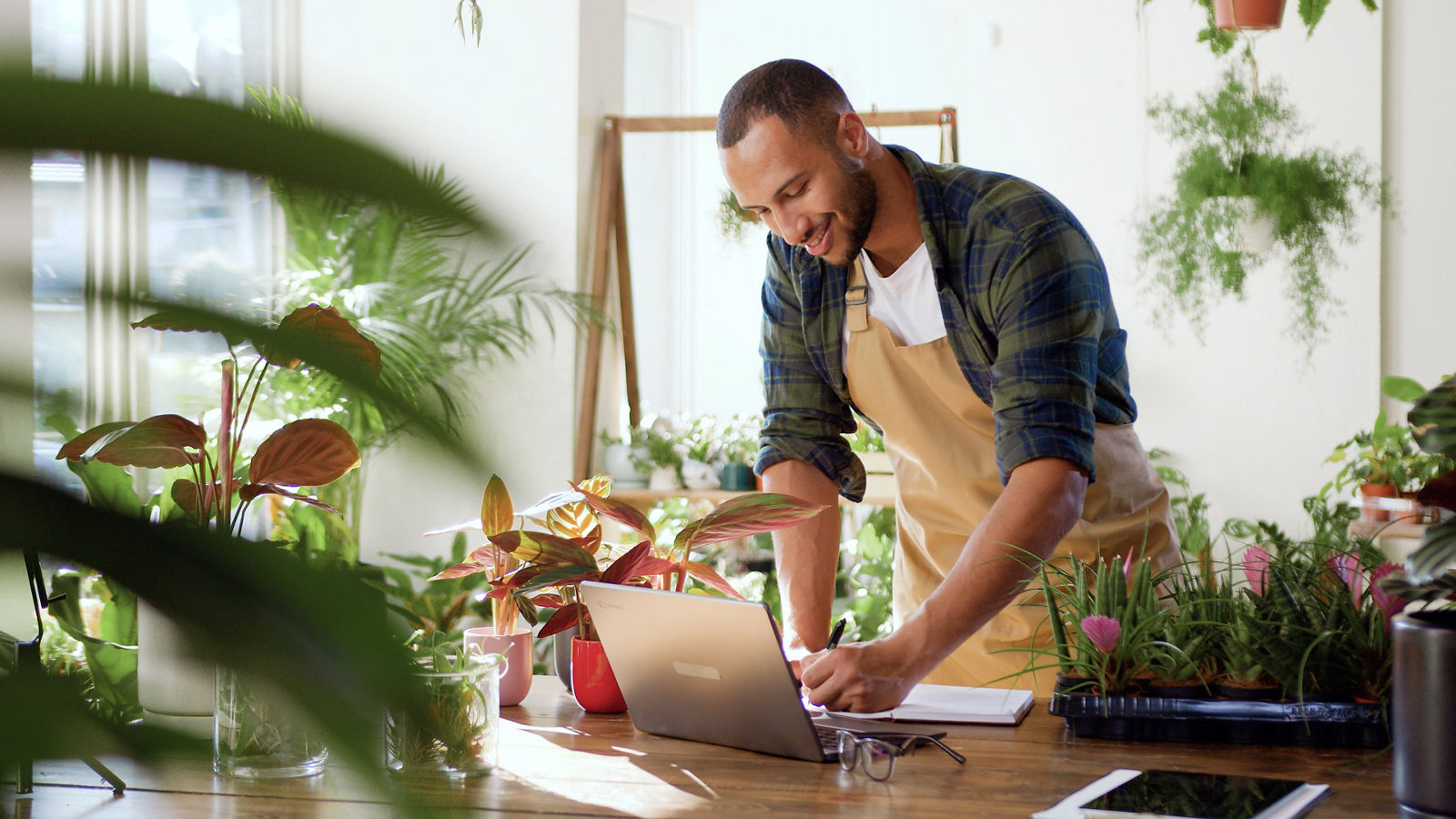 Florist shop owner looking at computer writing down notes