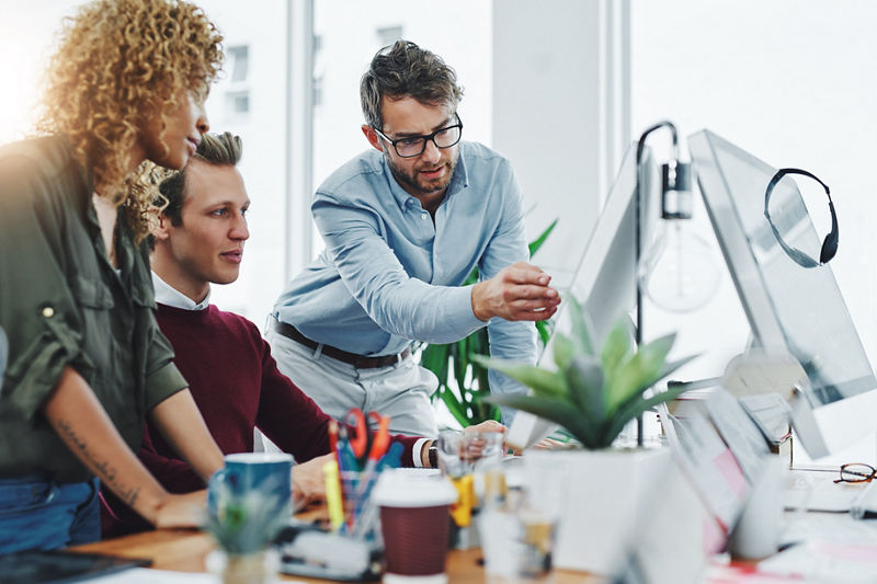 Shot of a group of colleagues using a computer together in a modern office