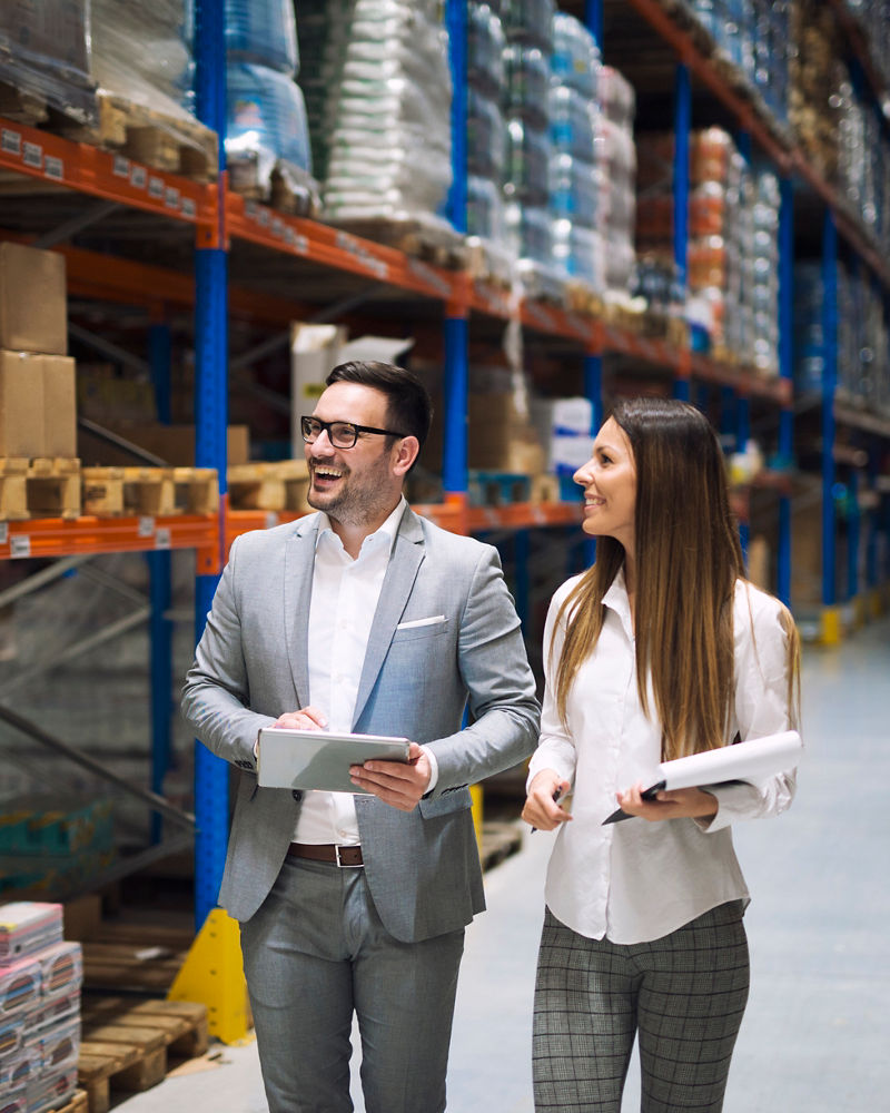 Two business people walking through large warehouse