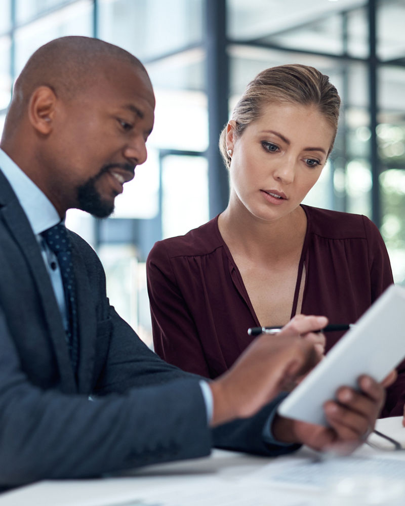 Shot of a businessman and businesswoman using a digital tablet together in a modern office