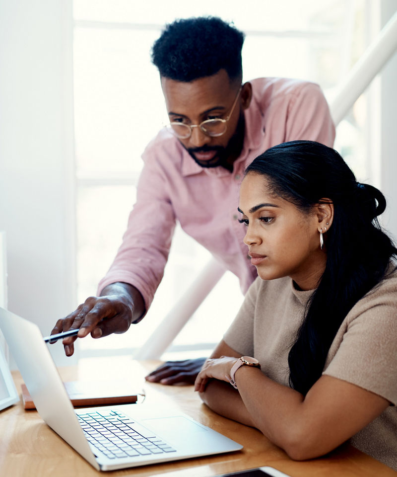 Two young businesspeople sitting in the office and working on a laptop together