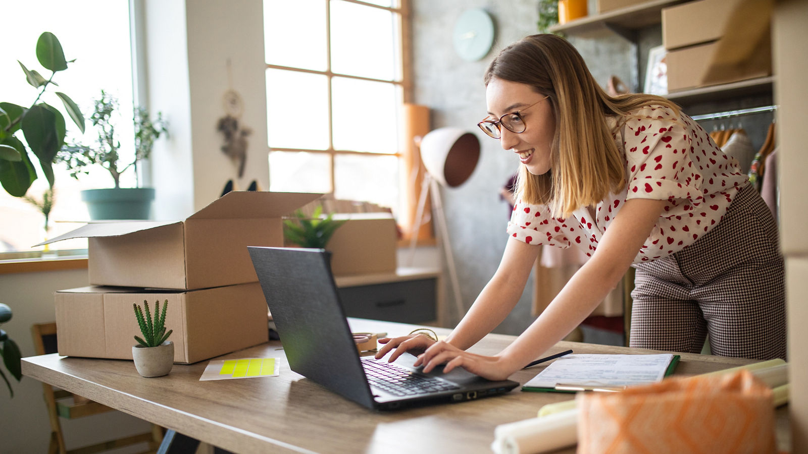 Young female entrepreneur receiving new orders in her e-commerce clothing shop