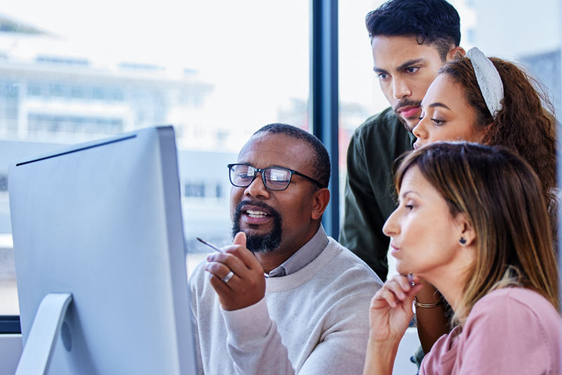 Group of workers in office looking at computer monitor