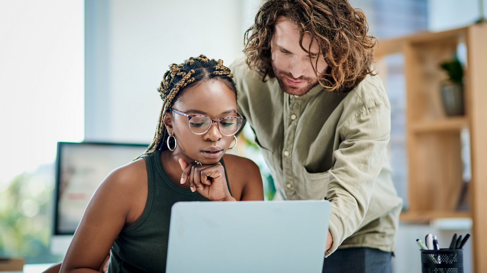 Two developers on laptop in office both looking at screen intently