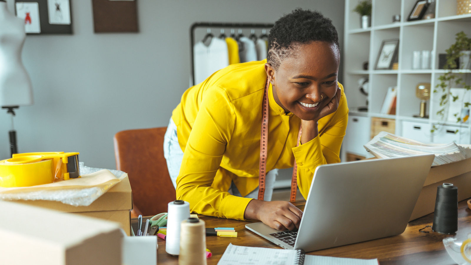 Caucasian businessman is sitting in an office and having a meeting with a female colleague. He might be working from home. It's morning or later in the day. He is smiling. A laptop is in front of him and the woman is holding a digital tablet.
