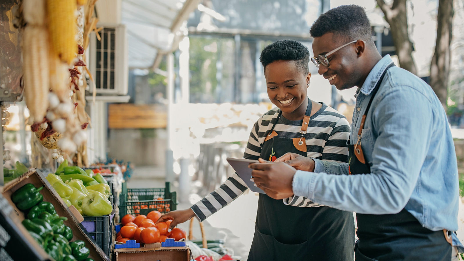 Two small business owners working in the fruit and vegetable store checking digital tablet