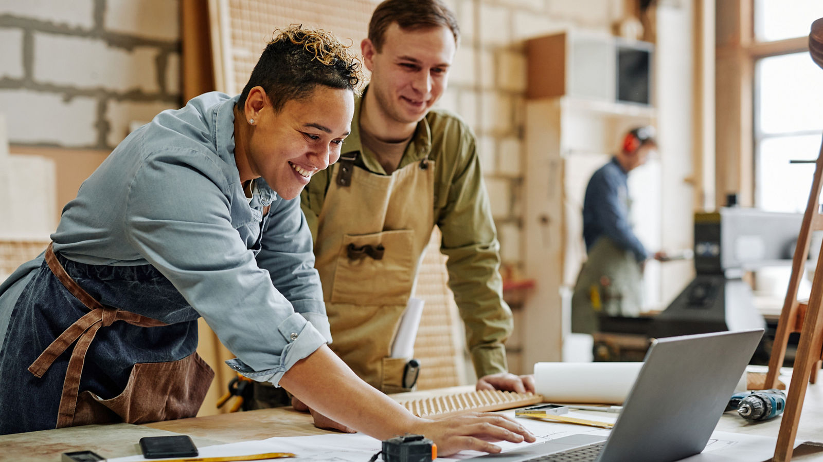 Two small business owners working on laptop in carpentry business shed