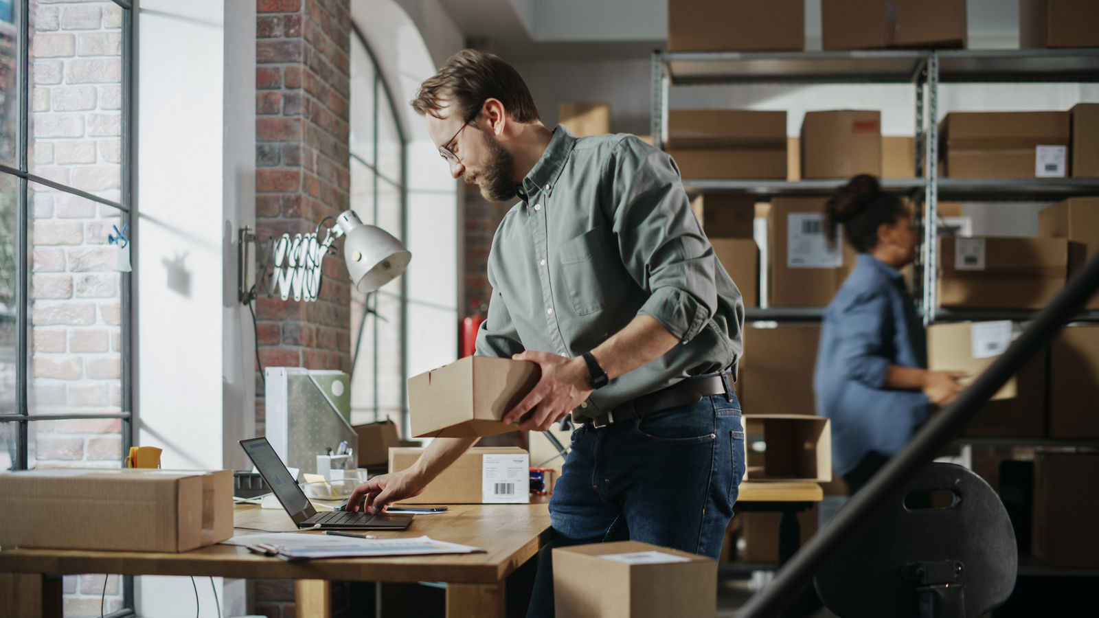 Small business owner looking at contract holding a box in warehouse