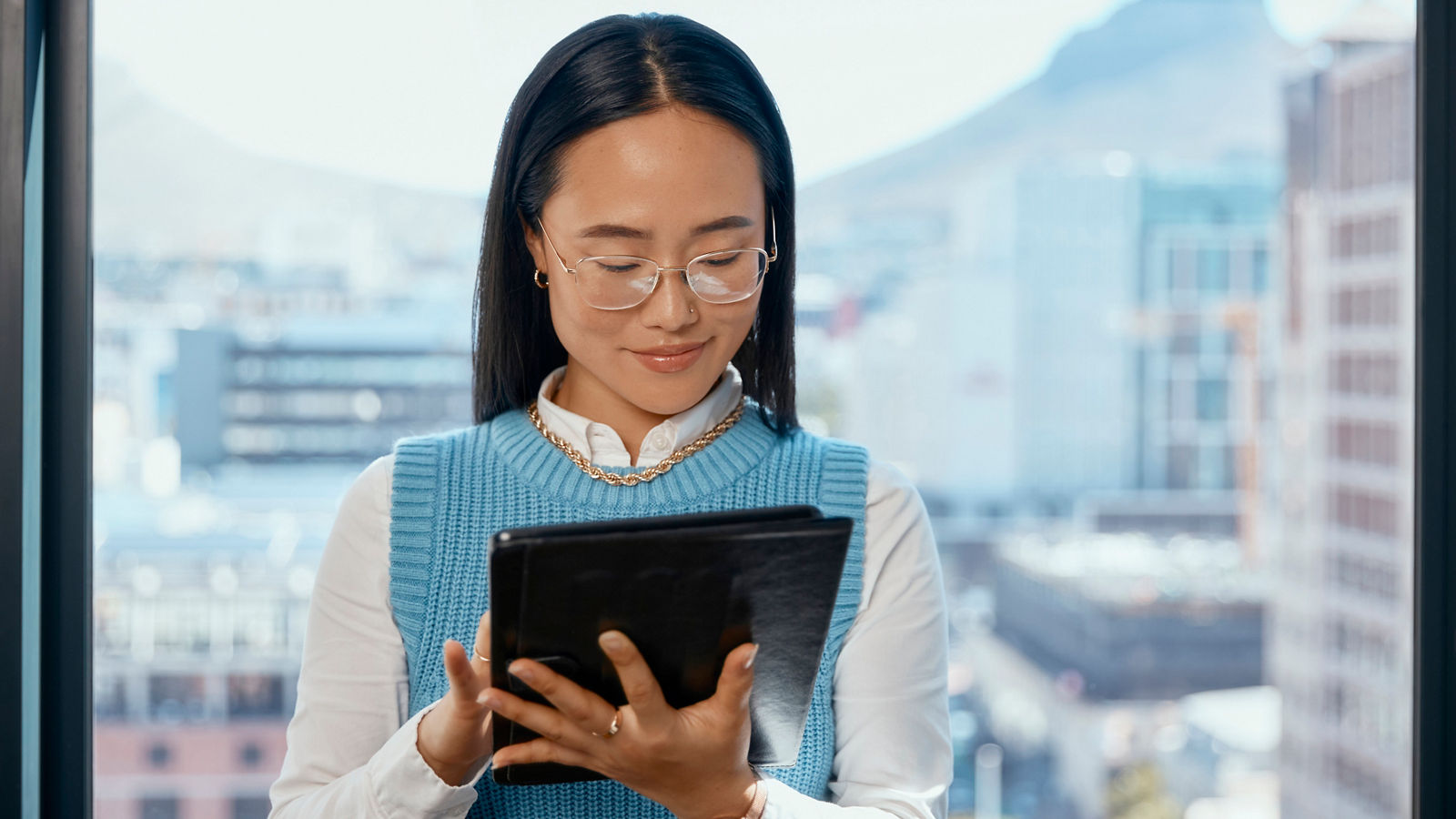 Woman in glasses staring at tablet happy in office