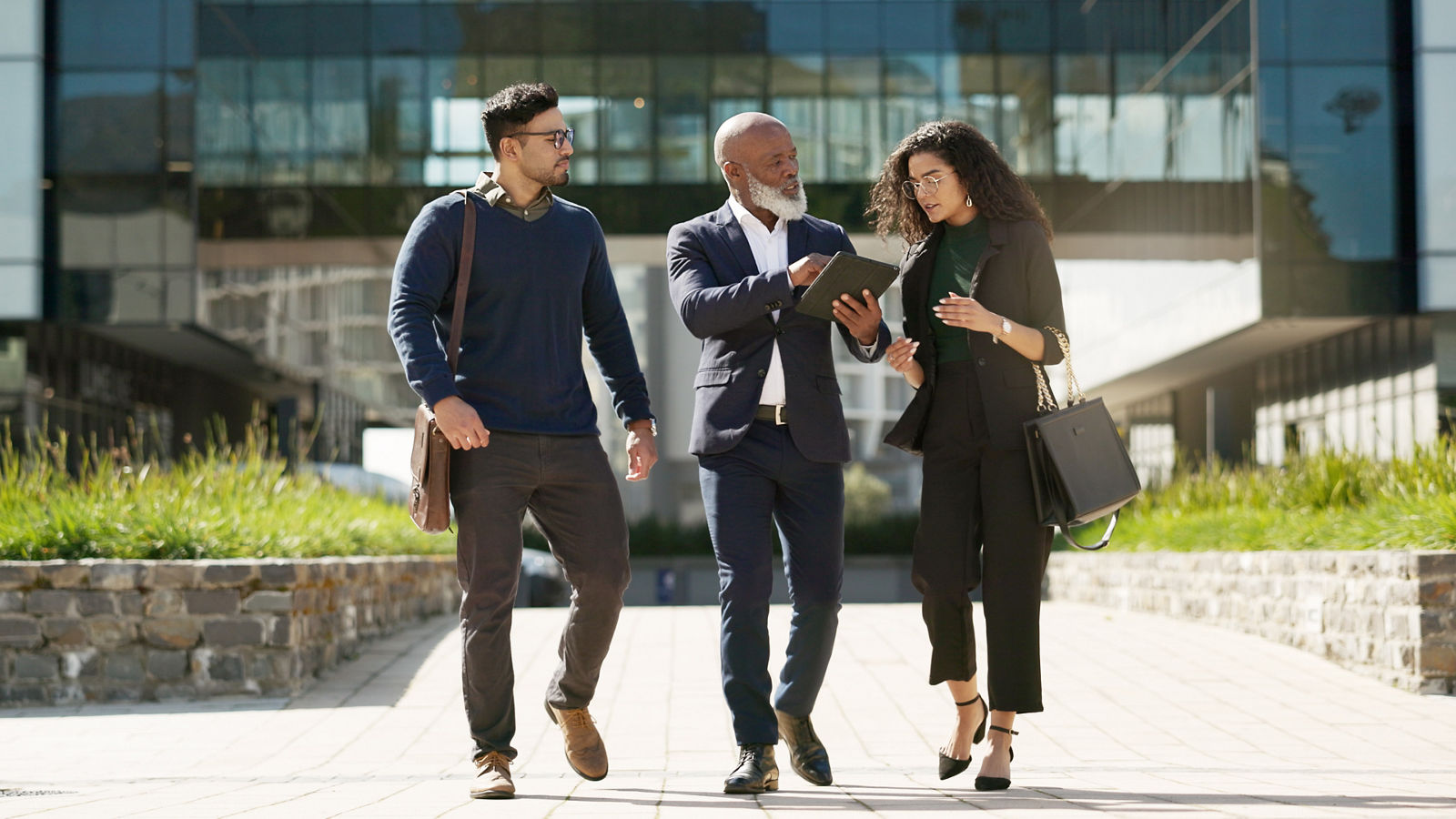 Walking compliance workers talking over iPad outside of office