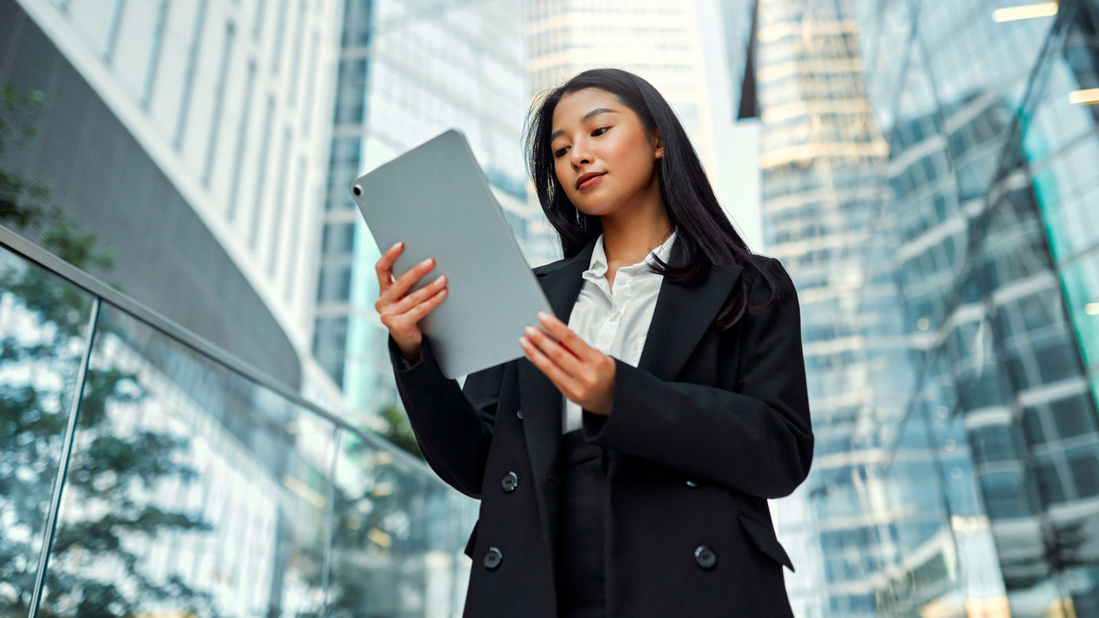 Businessman is sitting in an office and having a meeting with a female colleague. He might be working from home. It's morning or later in the day. He is smiling. A laptop is in front of him and the woman is holding a digital tablet.