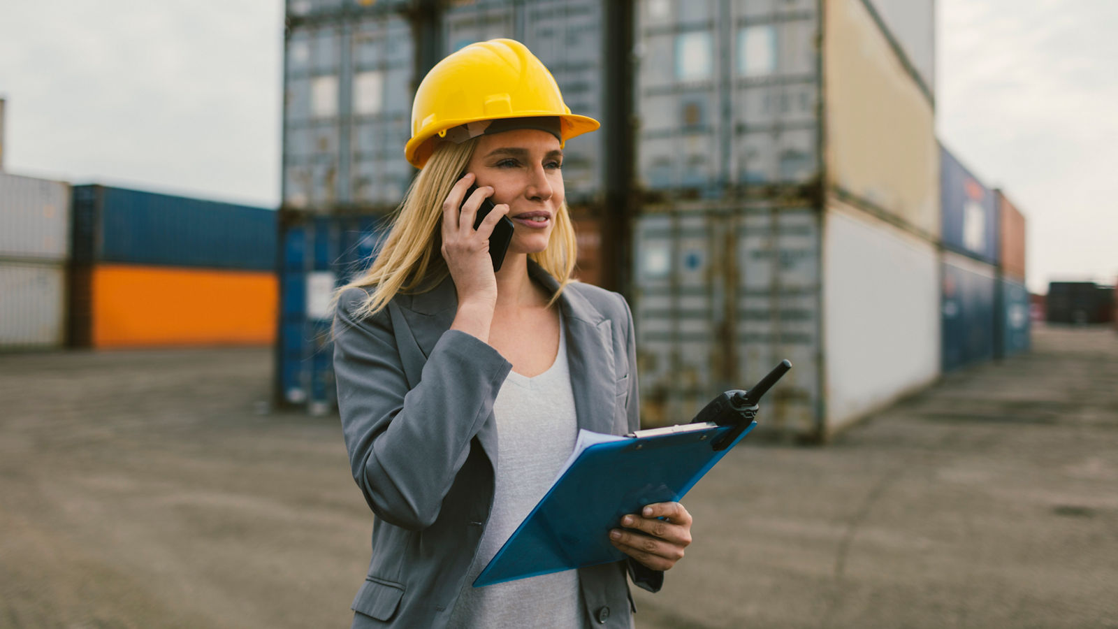 Business woman in cargo ship yard on walkie-talkie