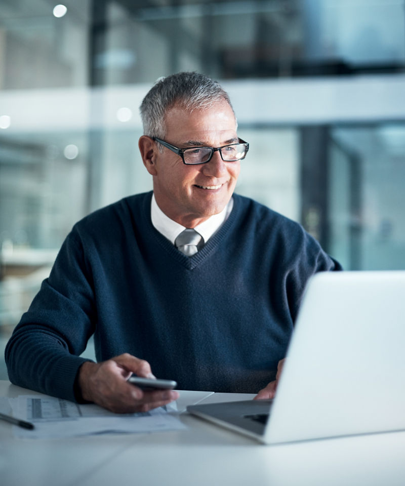 Man working in bank smiling at laptop