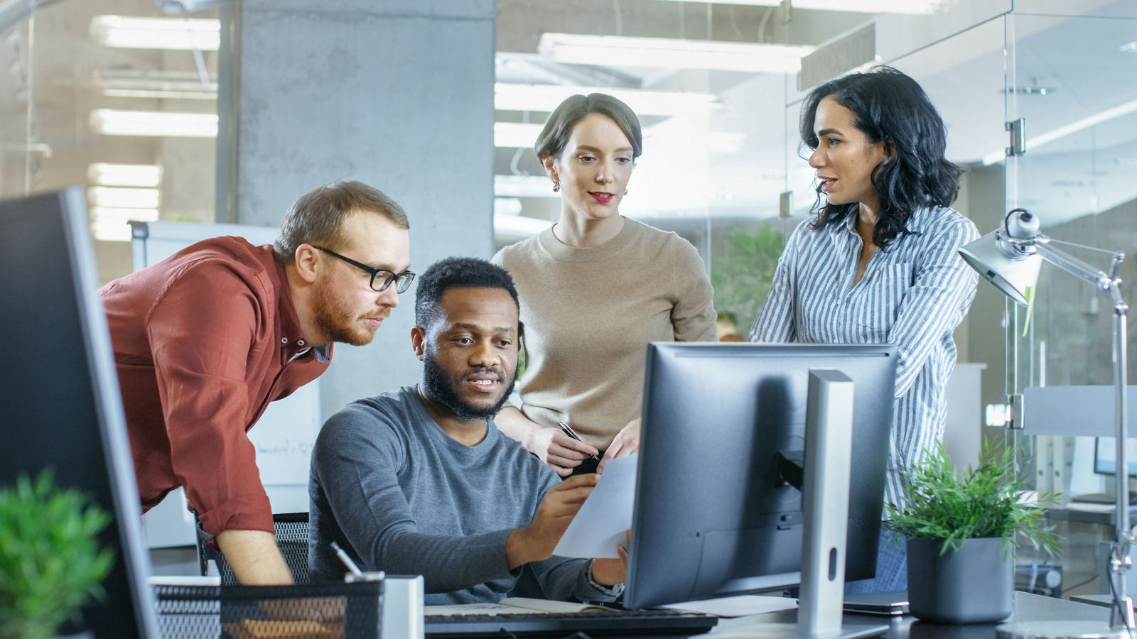 Group of workers looking at computer having conversation