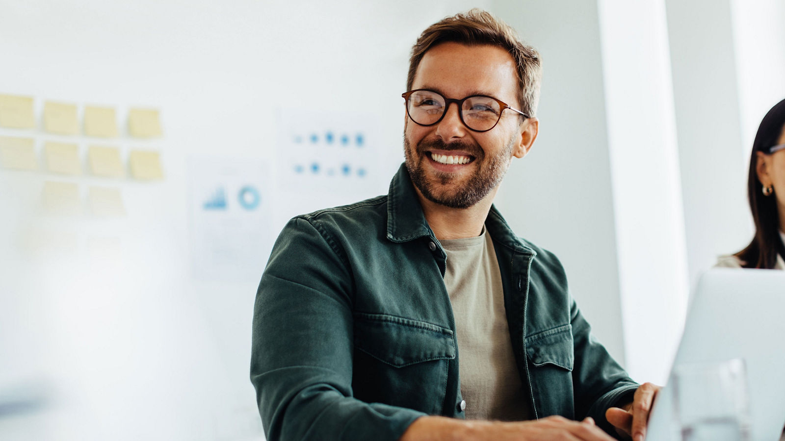 Man smiling with laptop in a meeting