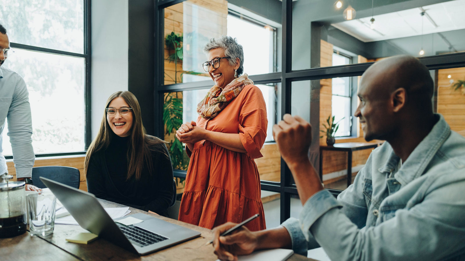 Businesspeople smiling cheerfully during a meeting in a modern office.