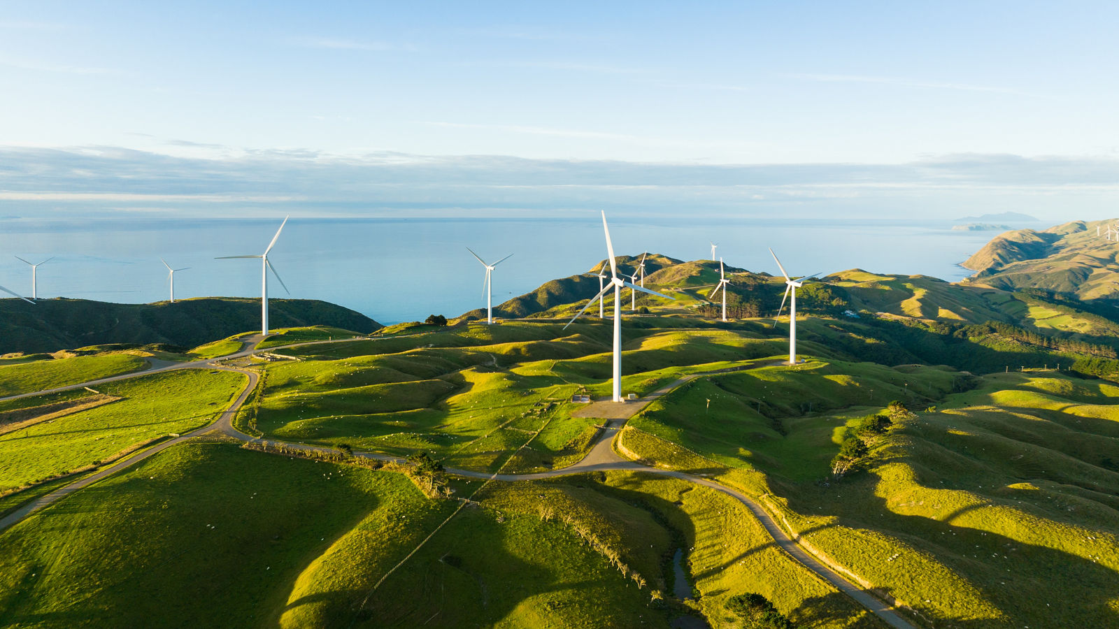 Beautiful scenic view of wind turbines scattered across the hills with coast in backdrop