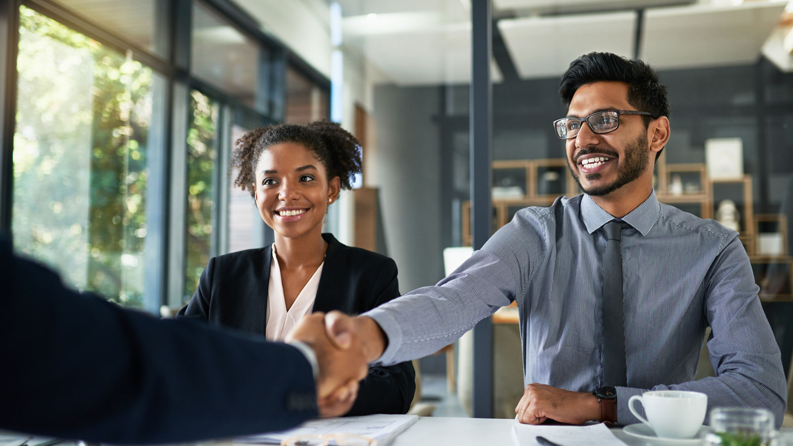 Two businesspeople shaking hands while in a meeting