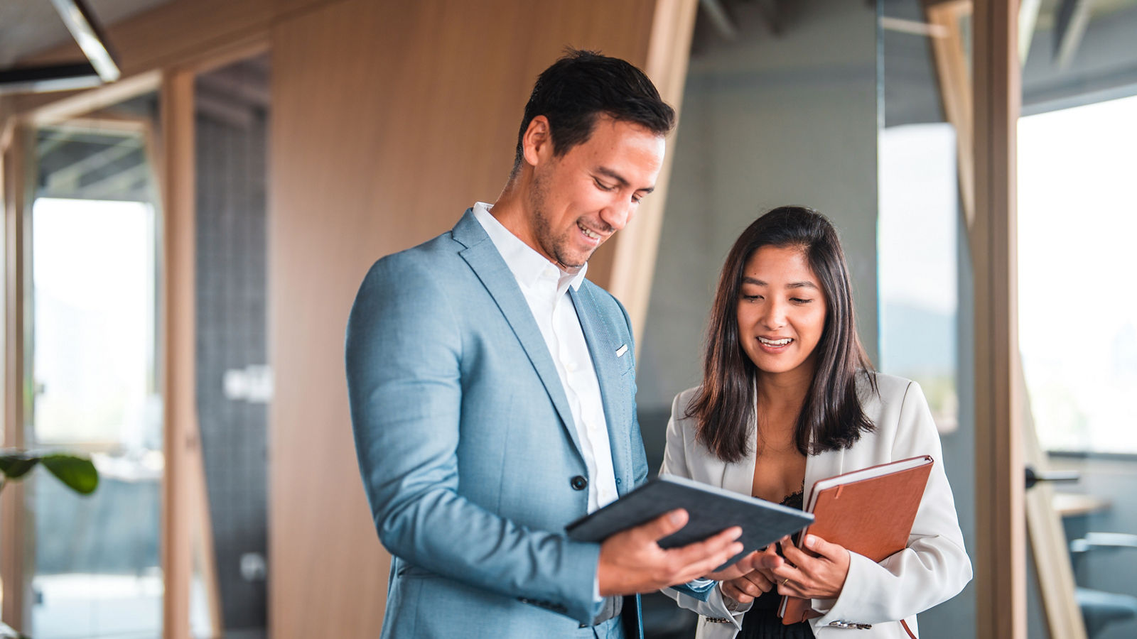 Two people talking in an office. They are referencing a tablet.