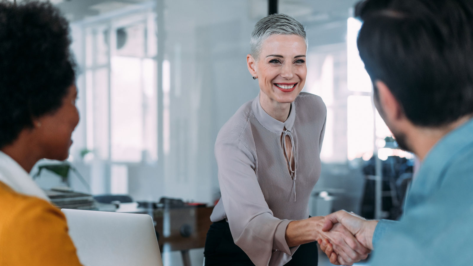 Business people handshaking across the table during a meeting in modern office. Group of business persons in business meeting.