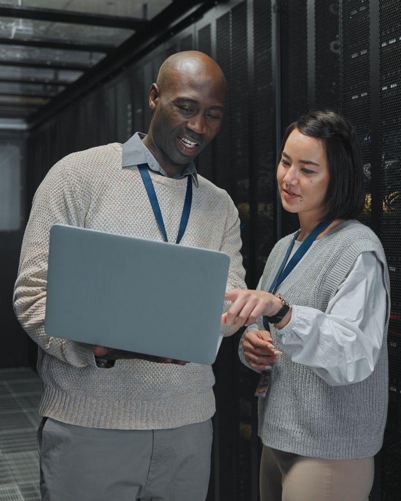 Man and woman looking at laptop inside of server room