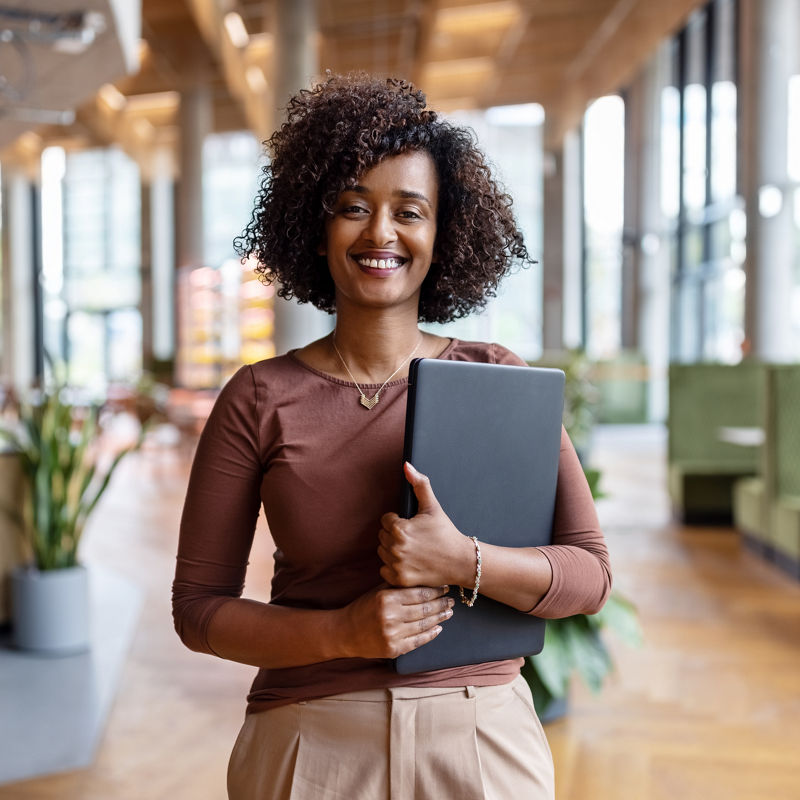 Portrait of happy businesswoman holding digital tablet standing in the office. Female entrepreneur at her startup office looking at camera and smiling.