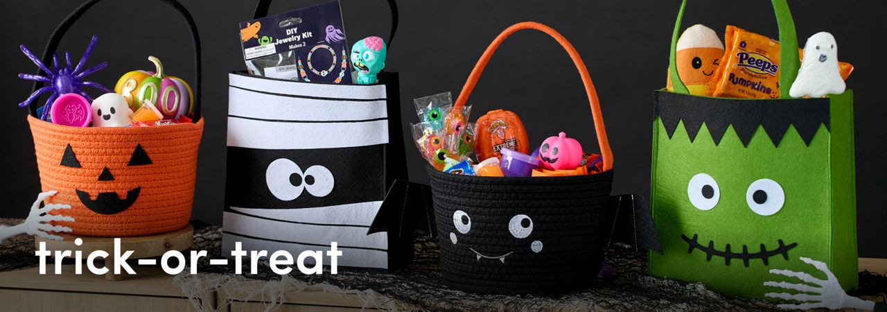 Pumpkin, mummy, bat and Frankenstein themed candy baskets are filled with various Halloween themed toys and decor.