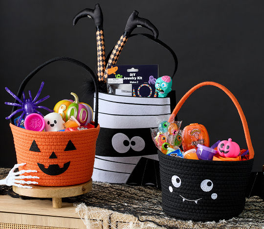 Pumpkin, mummy, and bat themed candy baskets are filled with various Halloween themed toys and decor.