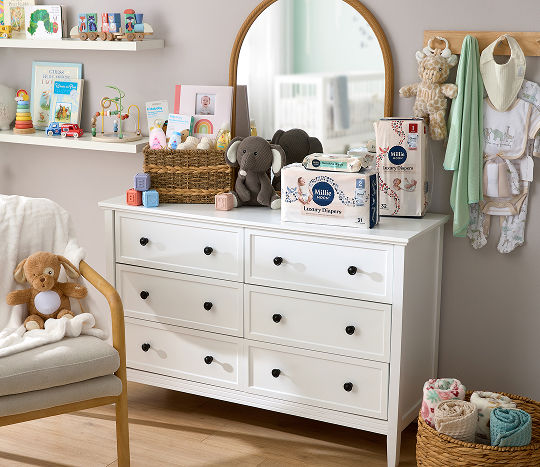 A nursery is decorated with gender neutral baby supplies including plush animals, diapers, and more.