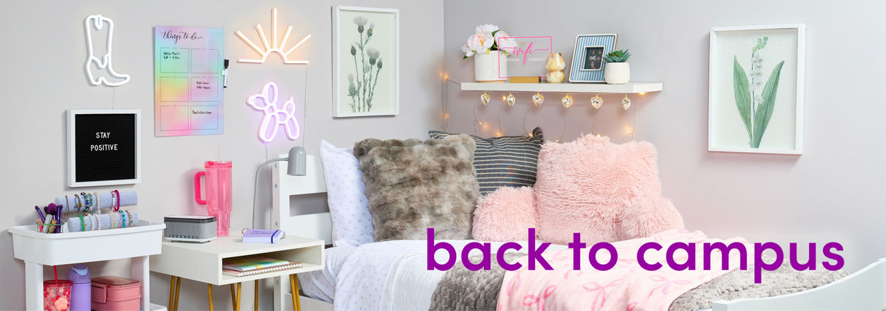 Dorm room decorated with pastel and neautral tones: pink & gray throws, pink furry study pillow, white storage cart, wall lights, sheets & more.