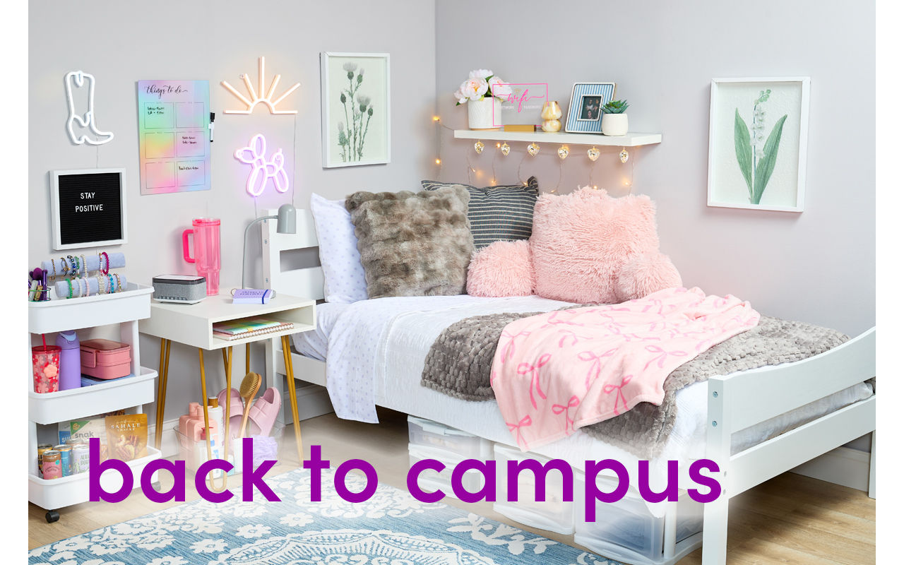 Dorm room decorated with pastel and neautral tones: pink & gray throws, pink furry study pillow, white storage cart, wall lights, sheets & more.
