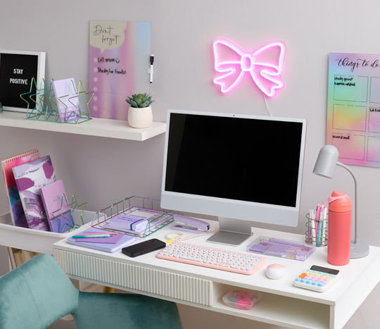 Study desk with pastel desk accessories: pink keyboard and mouse, colorful calculator, wire desk organizers, markers, pens & more.. 