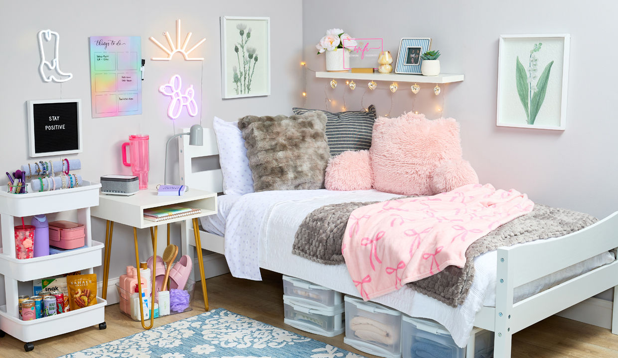 Decorated dorm with pink throw, pink study pillow, underbed plastic storage, fun lights and decor, with bath supplies, water bottles, snacks & more.