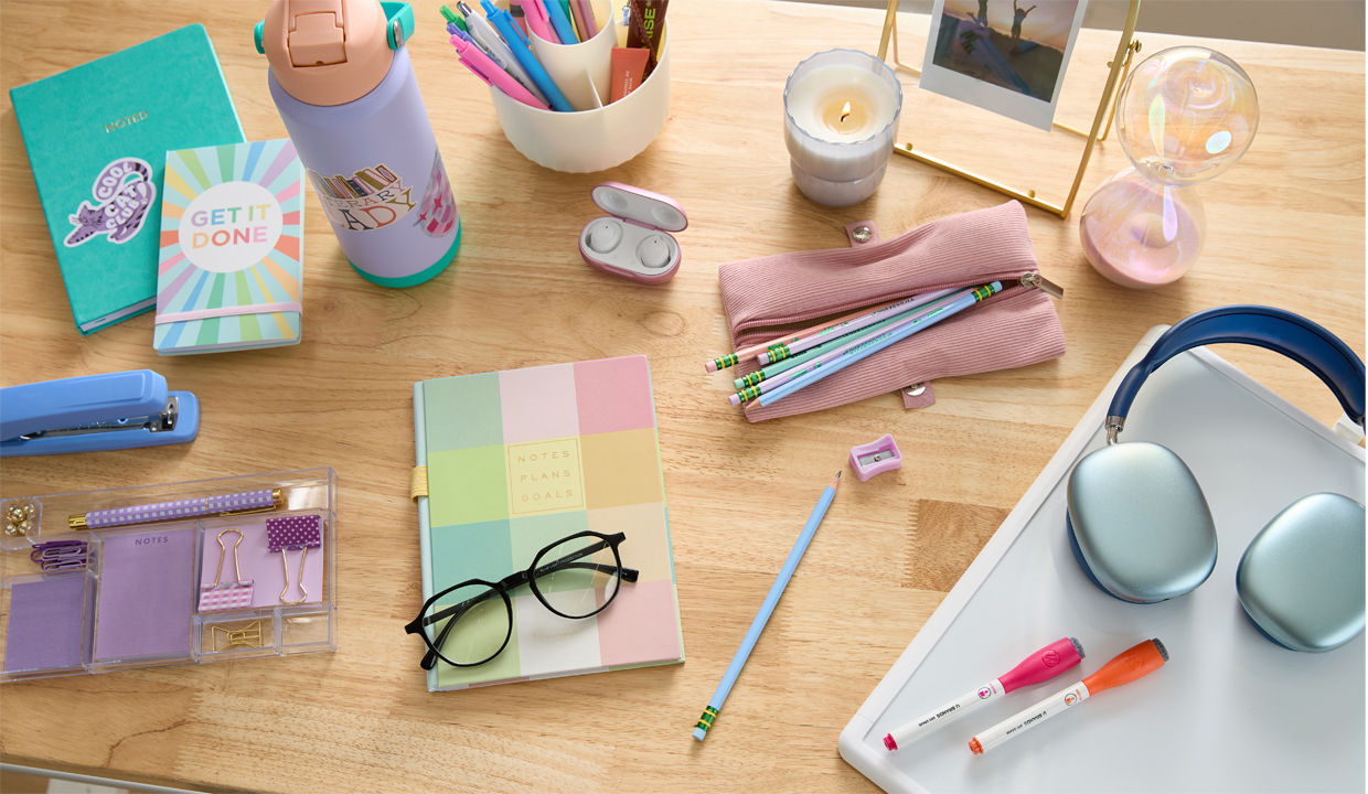 Pastel back-to-school supplies: spiral notebooks, pink bow pencil pouch, pens & pencils, calculator, water bottle with sticker, earbuds, headphones & more.
