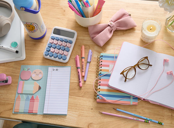 Pastel back-to-school supplies: spiral notebooks, pink bow pencil pouch, pens & pencils, calculator, water bottle with sticker, earbuds, headphones & more.