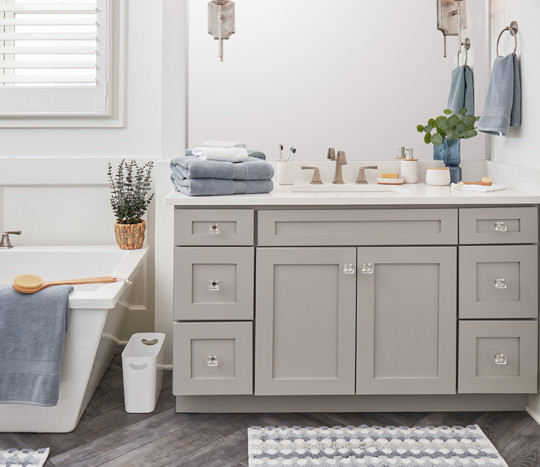 New blue, gray & white towels, rugs, bathroom accessories, and decor in a bathroom with gray cabinets.