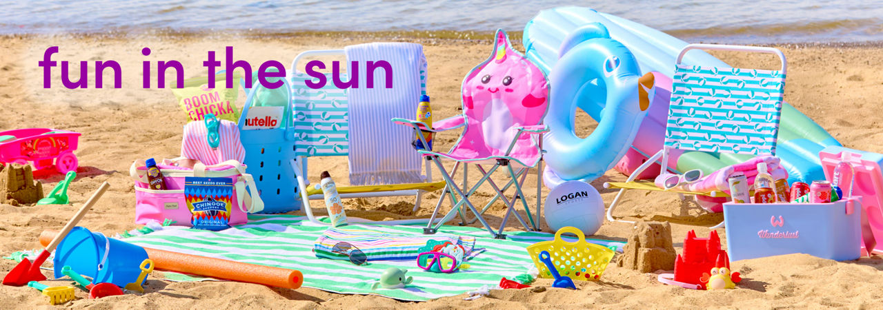 Beach scene with folding beach chairs, beach umbrella, beach towels, insulated coolers & sand toys.