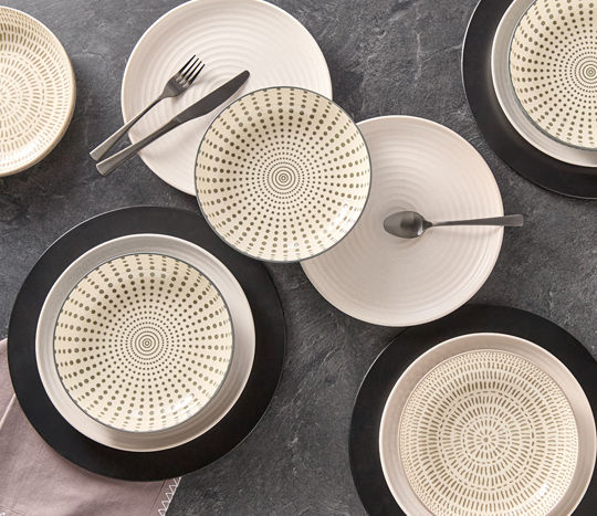 White plates with black and white patterned plate bowls and black chargers.