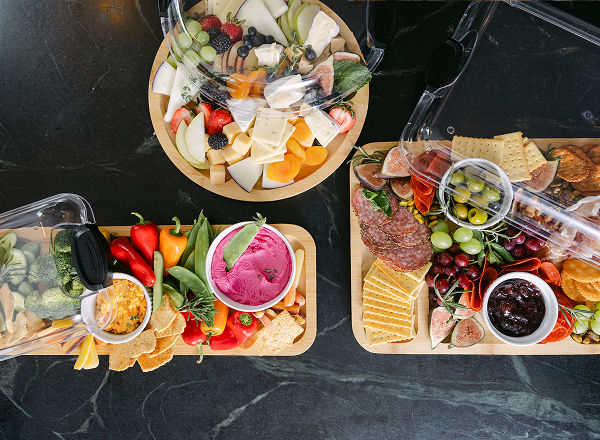 Several charcuterie boards in various shapes feature charcuterie snacks arranged among the boards.