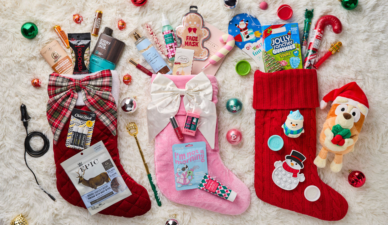 Christmas stockings laid on floor with items spilling out including snacks, deodorant, face mask, body spray, etc.