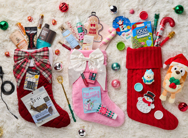 Christmas stockings laid on floor with items spilling out including snacks, deodorant, face mask, body spray, etc.