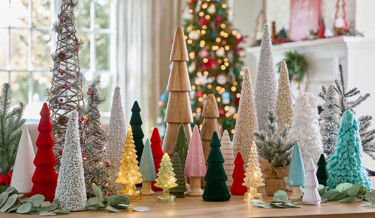 Table with various Christmas tree decor in glass, ceramic, fabric, wood, and more.