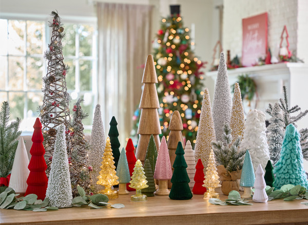 Table with various Christmas tree decor in glass, ceramic, fabric, wood, and more.