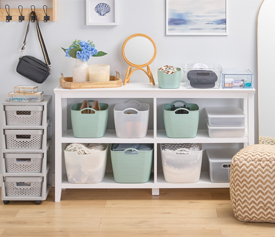 Plastic baskets in mint and clear, clear plastic storage containers, wall hooks, and a 4-drawer storage caddy help organize a walk-in closet.