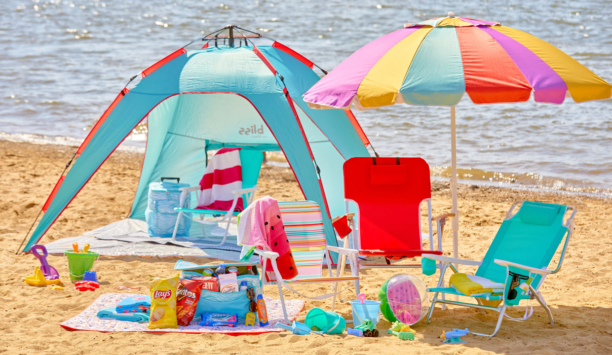 Beach scene with folding beach chairs, beach umbrella, beach tent, beach towels, insulated coolers & sand toys.