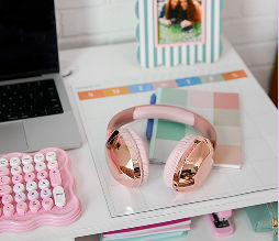 A dorm room desk featuring headphones, a keyboard, and other affordable study essentials from pOpshelf.