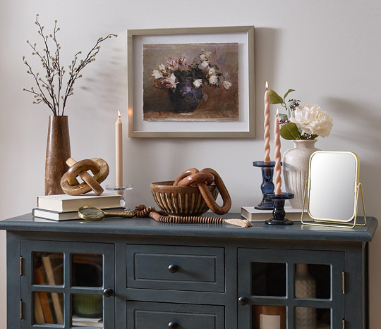 Wooden bowl and decor pieces, Ceramic vases, taper candles, blue glass candleholders, a gold edged mirror, and floral wall art from pOpshelf.