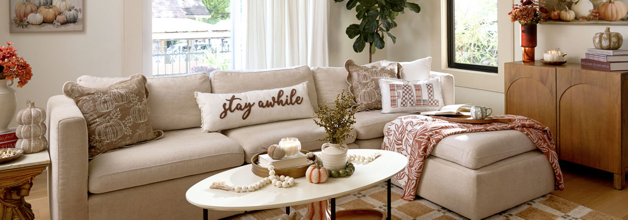 A living room with neutral colored decor features fall accents like affordable pumpkin themed decor from pOpshelf.
