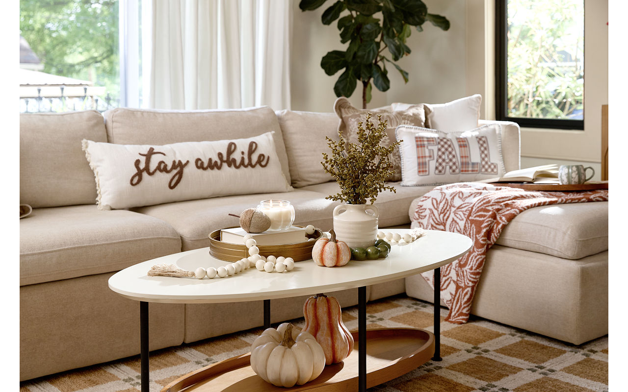 A living room with neutral colored decor features fall accents like affordable pumpkin themed decor from pOpshelf.